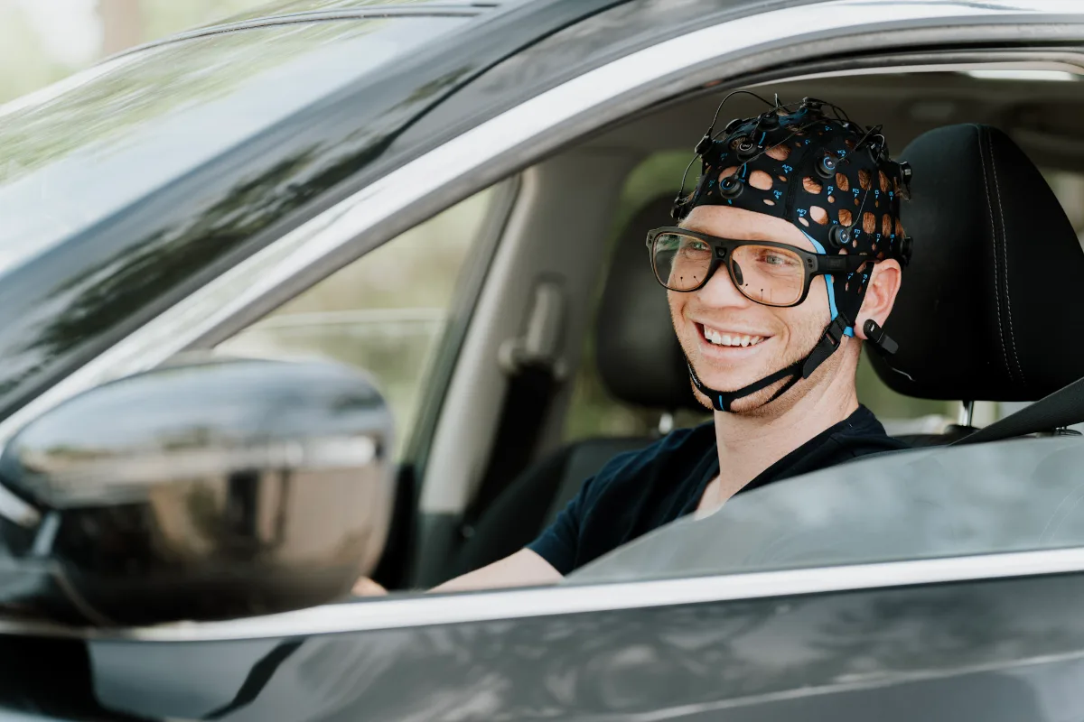 Driver wearing Bitbrain Versatile Plus EEG cap with Tobii eye tracking in a car